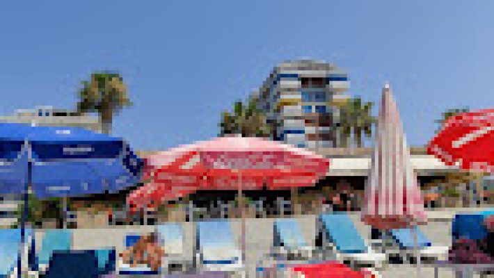 Jungleman Amigos Beach Club’un palmiye ağaçlarıyla çevrili sahil manzarası ve renkli atmosferi