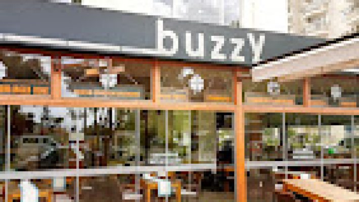 Buzzy Mahmutlar’da modern cafe ve bar alanı, masalarda içecekler ve rahat oturma alanlarıyla misafirlerin keyifli vakit geçirdiği ortam.