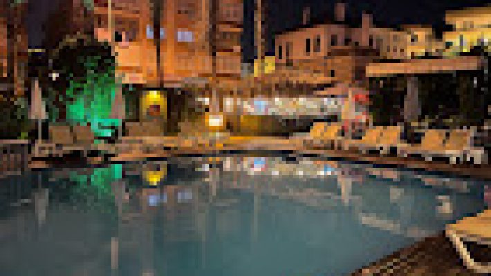 HMA Hotel & Suites Alanya’da modern otel binası, açık havuz ve şezlonglarla lüks konaklama alanı.