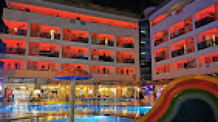 Blue Wave Hotel Alanya’nın açık havuzu, şezlonglu güneşlenme alanı ve modern otel binasının genel görünümü