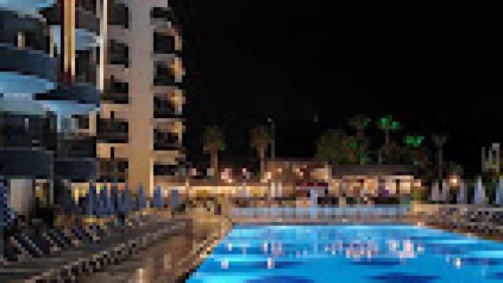 Grand Uysal Beach & Spa Hotel’in denize sıfır konumlu büyük açık havuzu, otel binası ve Akdeniz manzarasıyla birlikte güneşli bir yaz gününde çekilmiş görseli