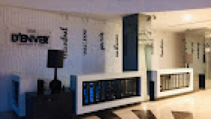 D'ENVER LEATHER mağazasında deri ceket, çanta ve aksesuarların şık bir şekilde sergilendiği iç mekan görünümü.