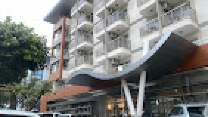 Grand Okan Hotel’in modern mimarili binası, geniş açık yüzme havuzu ve Kleopatra Plajı’na bakan konumuyla birlikte güneşli bir günde görüntülenmiş